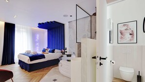 Een moderne slaapkamer met een bed, nachtkastje en een badkamer met toilet en douche.