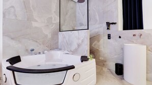 Een moderne badkamer met een ruime badkuip, een aparte douche en een groot wastafel.