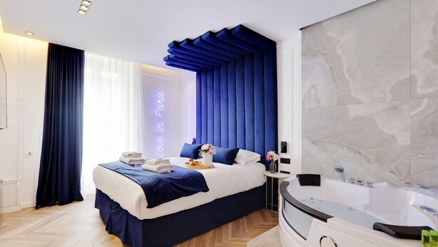 Een moderne slaapkamer met een groot bed, een inbouww bad en een marmeren wand.