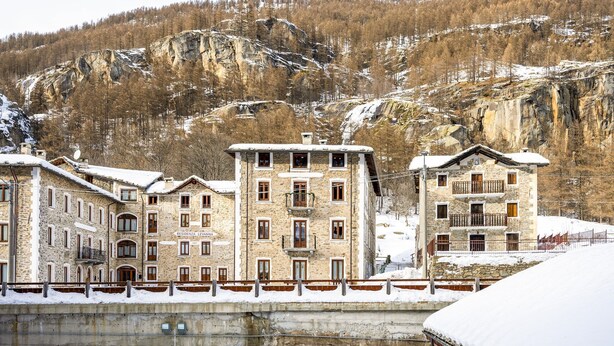 A stone building with multiple windows and balconies, a snow-covered roof, and a mountainous backdrop. - In the historic building, con aria condizionata (Ceresole Reale (TO))