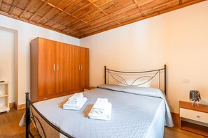 Un dormitorio con un armario de madera, una estructura de cama de metal y una mesita de noche con lámpara.