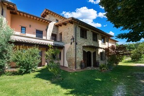 A two-story stone house with a balcony, surrounded by greenery. - Beautiful farmhouse with swimming pool (Città di Castello)