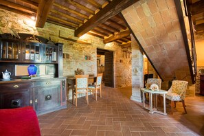 A rustic interior with exposed wooden beams, stone walls, a herringbone-patterned floor, and a wooden table with chairs. - Beautiful farmhouse with swimming pool (Città di Castello)