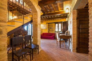 Un intérieur rustique avec un escalier en pierre, des meubles en bois et un canapé rouge.