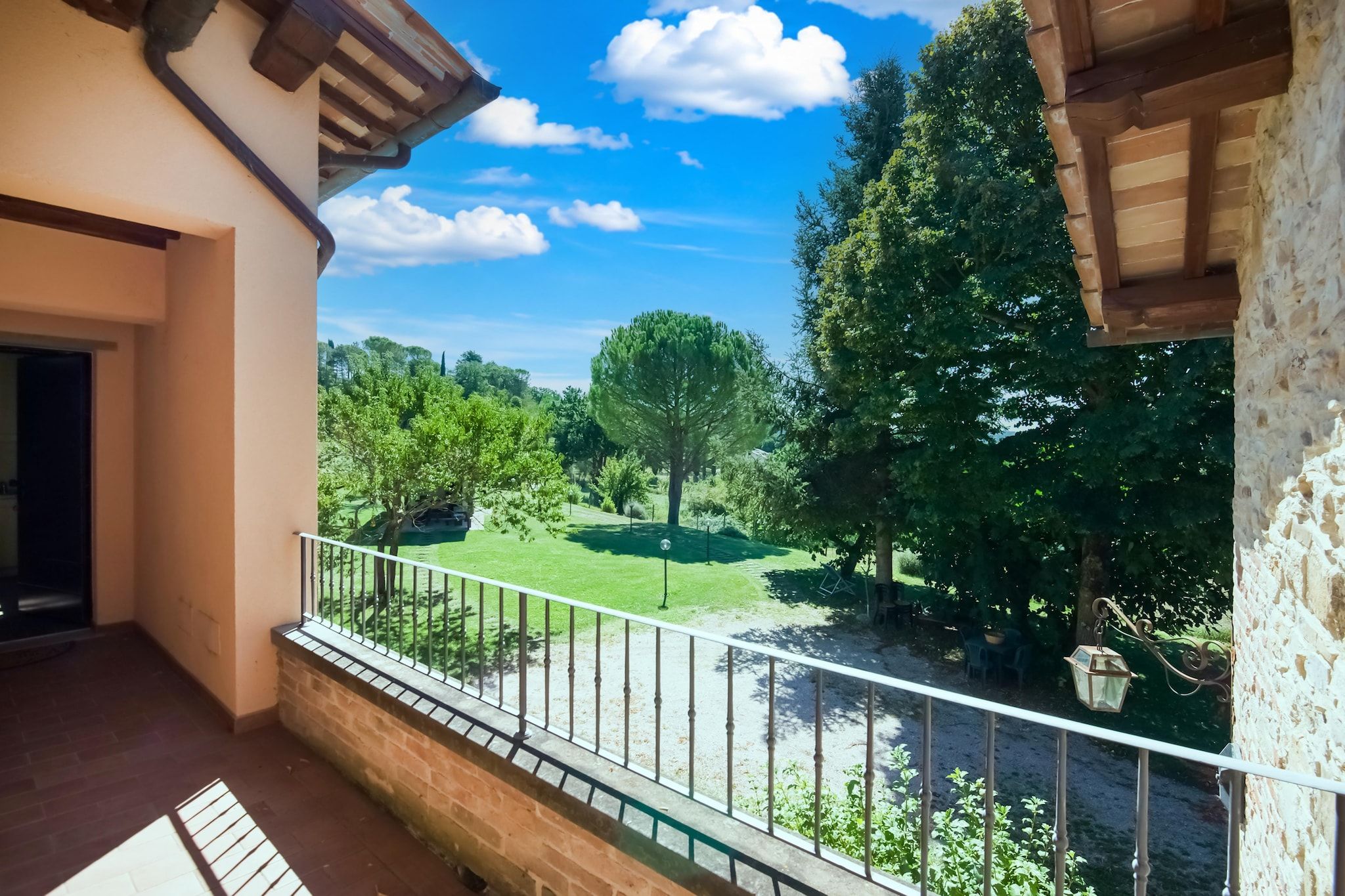 A balcony with a view of a green lawn and trees.