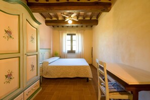 A bedroom with a bed, a chair, a window with curtains, and a radiator. - Beautiful farmhouse with swimming pool (Città di Castello)