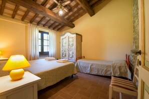 A bedroom with two beds, a wooden wardrobe, a lamp, and a window with curtains. - Beautiful farmhouse with swimming pool (Città di Castello)