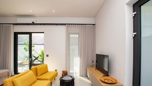 A modern living room with a yellow sofa, a small round table, and a TV on a wooden console.