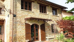 A stone building with a wooden porch, large windows, and a well-maintained garden.