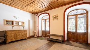 A room with a wooden ceiling, a large mirror, a wooden cabinet, a bench, and a door with glass panels.