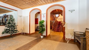 A spacious interior with wooden floors, a Christmas tree, a potted plant, and a staircase leading to a second floor.
