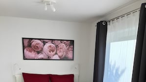 Una camera da letto con un letto, un comodino, una pianta in vaso e una finestra con tende.