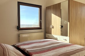 Une chambre à coucher avec un lit, une fenêtre, un radiateur et une armoire.