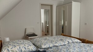 Une chambre avec deux lits, une chaise, une armoire et un miroir.