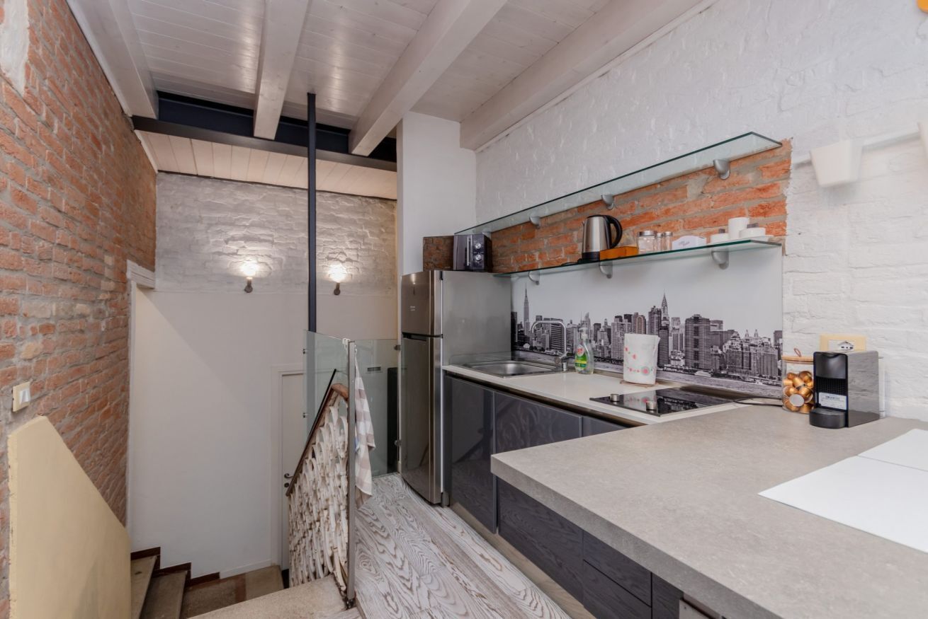 Een moderne keuken met een stadsgezicht als spatwand, een roestvrijstalen koelkast en een glazen plank met keukengerei.