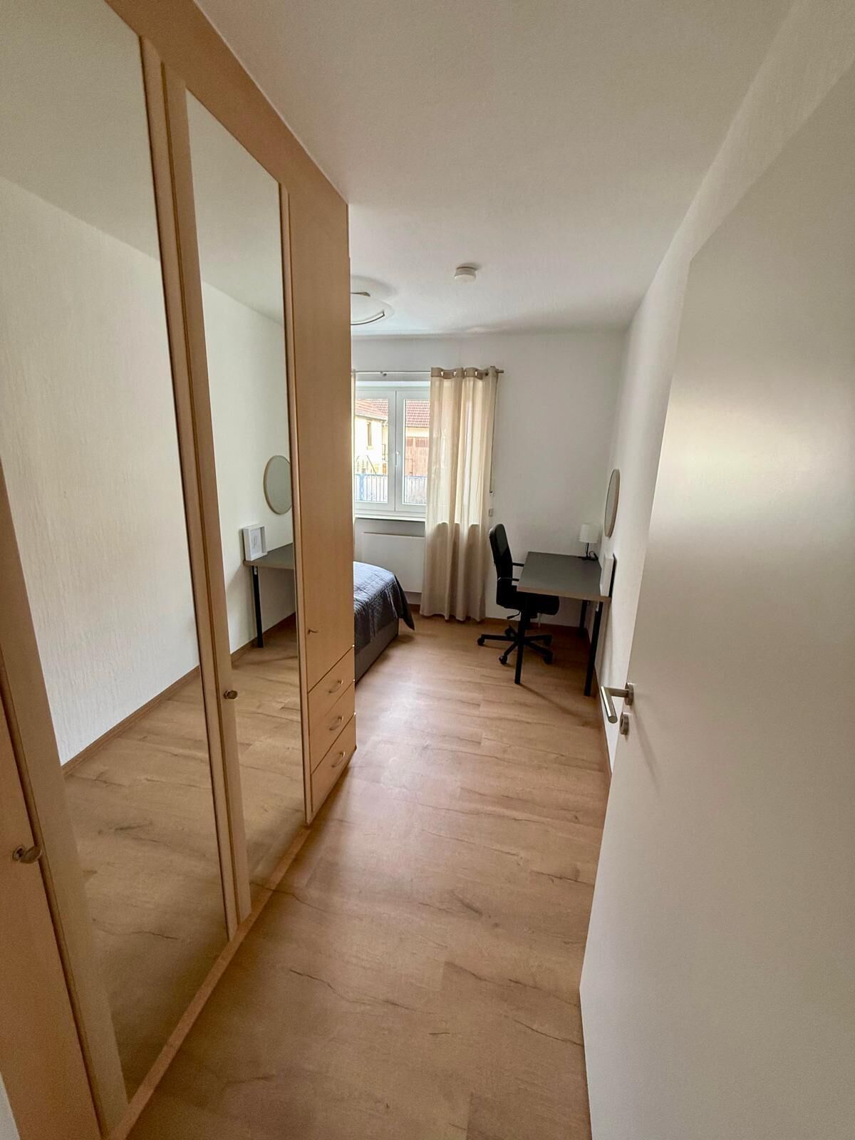 Une chambre avec un lit, un bureau, une chaise et une armoire.