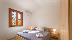 A bedroom with a bed, bedside tables, a wardrobe, and a window. - Spacious Flat 300mt From the Beach (Budoni)
