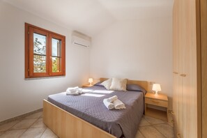 A bedroom with a bed, bedside tables, a wardrobe, and a window. - Spacious Flat 300mt From the Beach (Budoni)