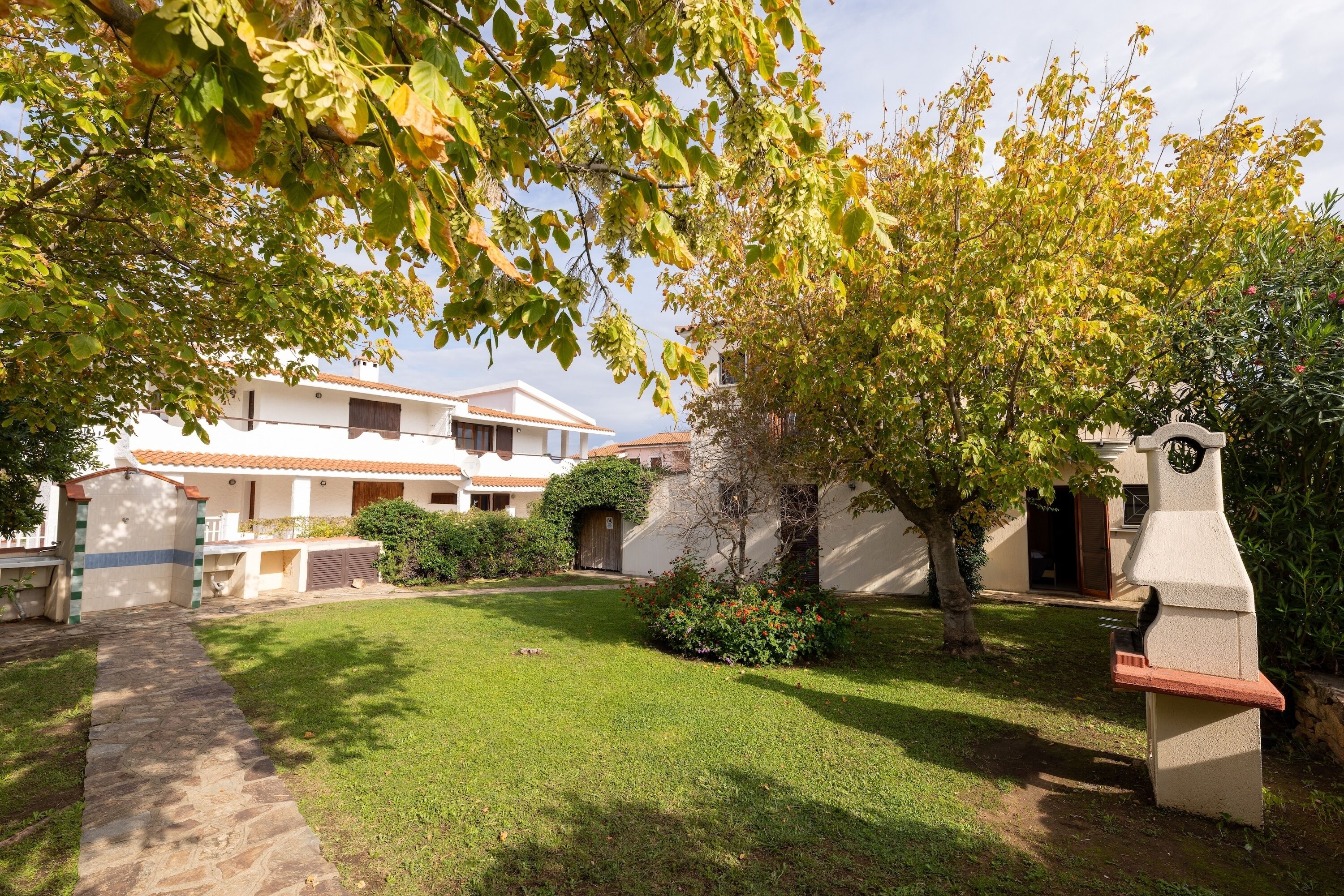 A courtyard with a stone pathway leading to a building with a tiled roof.