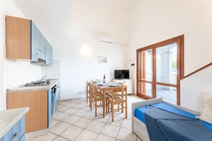 A compact kitchen with a dining area, a TV, and a window with blinds. - Spacious Flat 300mt From the Beach (Budoni)