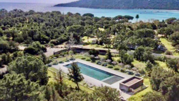 Et resort med en stor swimmingpool, frodigt grøntområde og havudsigt.