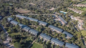 Oversigtsbillede af et resort med flere bygninger, en swimmingpool og en parkeringsplads.