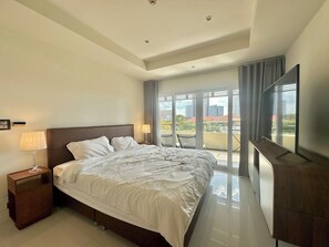 A modern hotel room with a large bed, a nightstand with a lamp, a flat-screen TV, and a balcony with a city view. - Pratumnak Hill - Family Suite 3 Bedroom Apartment Near Beach #VN Residence 2 (หนองปรือ)