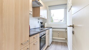 Eine moderne Küche mit Holzausstattung, einer schwarzen Arbeitsplatte, einem eingebauten Ofen und einem Fenster mit Blick nach draußen.