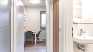 Een moderne badkamer met een witte wastafel, een chromen kraan en zichtbare leidingen.