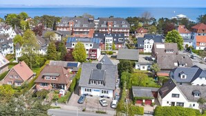A residential area with houses, some with solar panels, and a view of the sea. - Haus SeeZeit, Apartment 03 - Haus SeeZeit (Timmendorfer Strand)