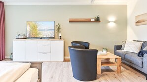 A modern living room with a sofa, a coffee table, and a TV on a cabinet. - Haus SeeZeit, Apartment 03 - Haus SeeZeit (Timmendorfer Strand)