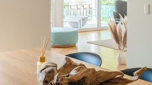 Moderni sisustus, jossa on puinen ruokapöytä, sininen tuoli ja näkymä ulkoterasille, jossa on pöytä ja tuoleja.