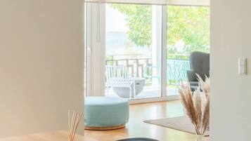 Un interior moderno con una mesa de comedor de madera, una silla azul y vistas a un patio exterior con una mesa y sillas.