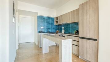 Una cocina moderna con una isla central, salpicadero azul y armarios de madera clara.
