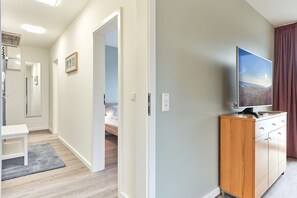 A hotel room with a bed, a TV, a wooden cabinet, and a desk. - Haus SeeZeit, Apartment 07 - Haus SeeZeit (Timmendorfer Strand)