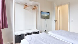 Een slaapkamer met twee bedden, een aan de muur bevestigde televisie en een raam met uitzicht.