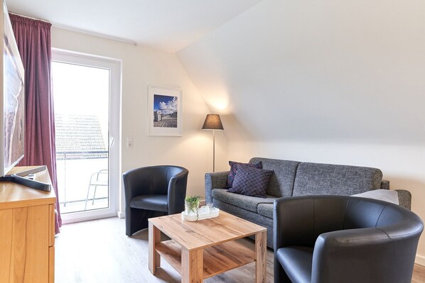 A modern living room with a grey sofa, two black armchairs, a wooden coffee table, and a floor lamp. - Haus SeeZeit, Apartment 07 - Haus SeeZeit (Timmendorfer Strand)