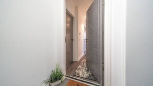 A hallway with a wooden door, a plant, and a star-patterned doormat. - Dockside: Quay Views, City Vibes (Dundee)
