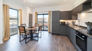 A modern kitchen with a dining area, large windows, and a view of the city. - Dockside: Quay Views, City Vibes (Dundee)