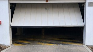 Une entrée de garage avec une porte métallique et une bande de sécurité jaune.