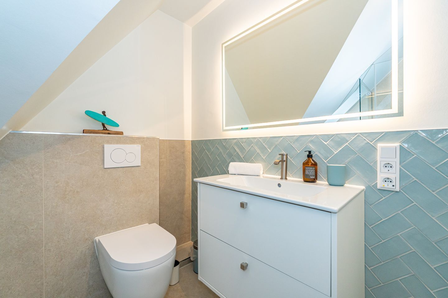 A modern bathroom with a white toilet, a sink with a mirror above it, and a tiled backsplash.