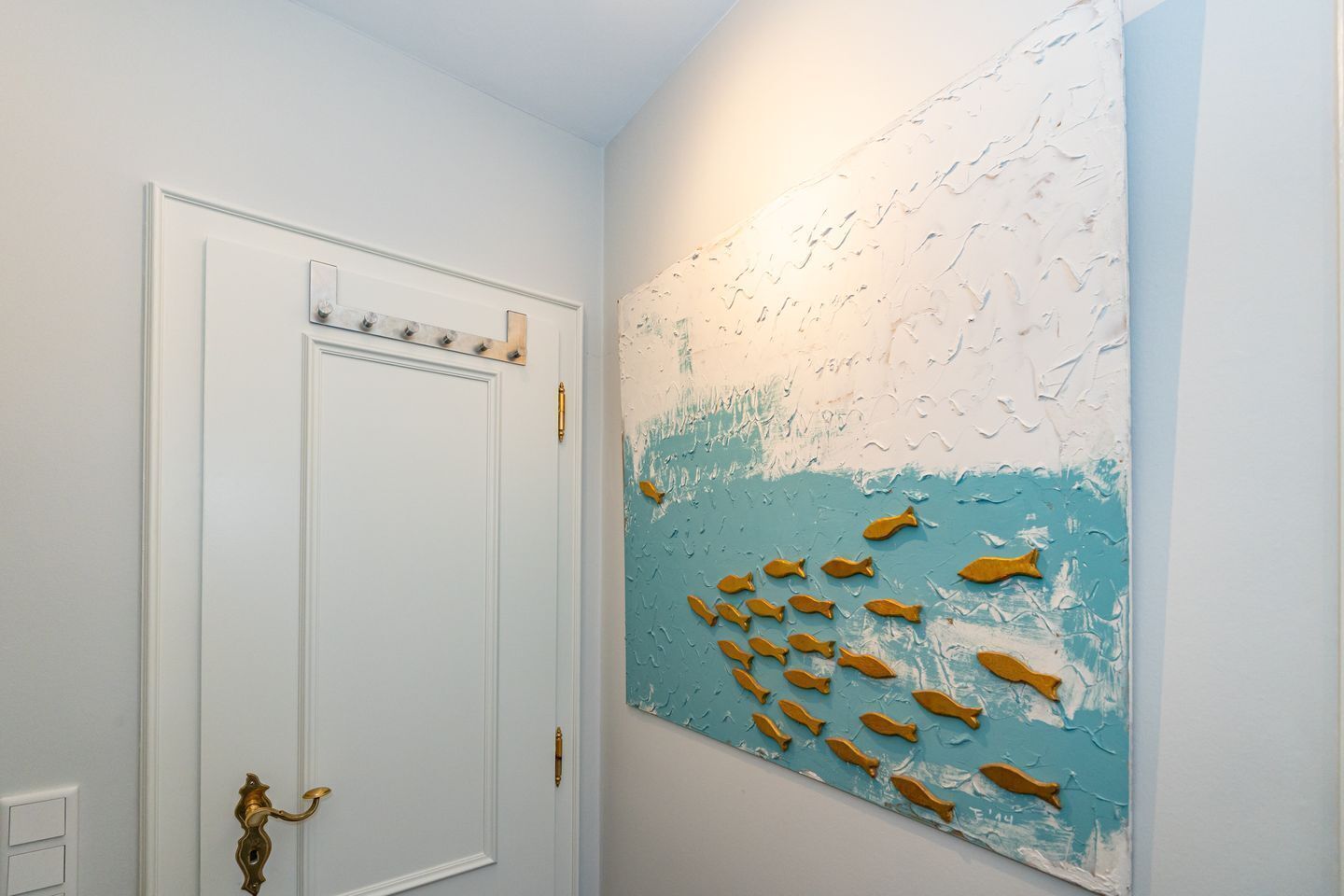 A hallway with a white door and a large wall painting of fish.