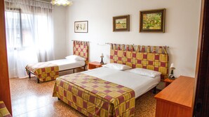 A hotel room with two beds, a wooden nightstand, a small table, and a window with curtains.