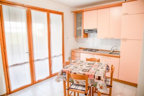 Una cucina con tavolo e sedie, lavello e pensili.