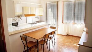 Une cuisine compacte comprenant une table à manger, des chaises, un four à micro-ondes, une cuisinière et des placards.