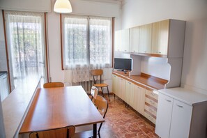 Uma cozinha compacta com mesa, cadeiras, televisão e armários.