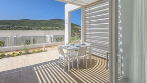 Ein Balkon mit Tisch und Stühlen, Blick auf eine grüne Landschaft und ein weißes Geländer.