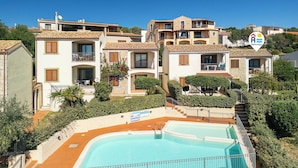 Zona residencial con piscina, edificios de varios pisos y un cartel que indica una ubicación.