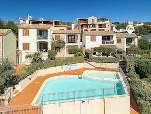 A residential area with a swimming pool, multiple-story buildings, and a sign indicating a location.