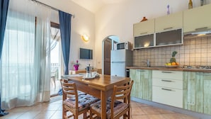 Una cocina con una mesa de comedor, sillas, refrigerador, microondas y salpicadero de azulejos.